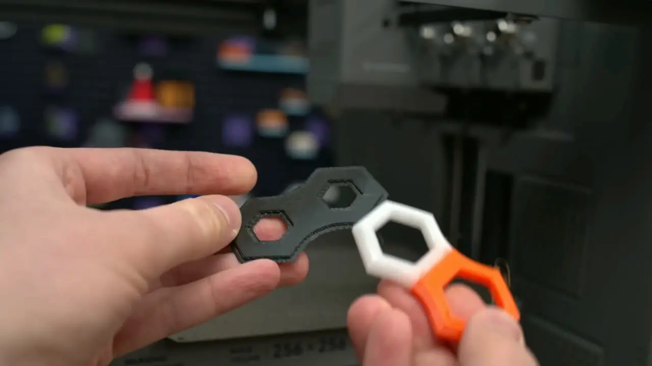 Hands holding black, white, and orange printed pieces with interlocking hexagonal openings