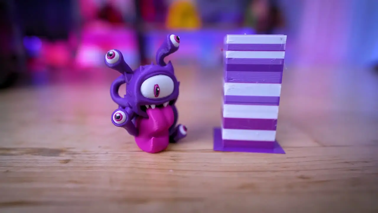 Purple, white, and pink printed monster beside a striped rectangular prime tower
