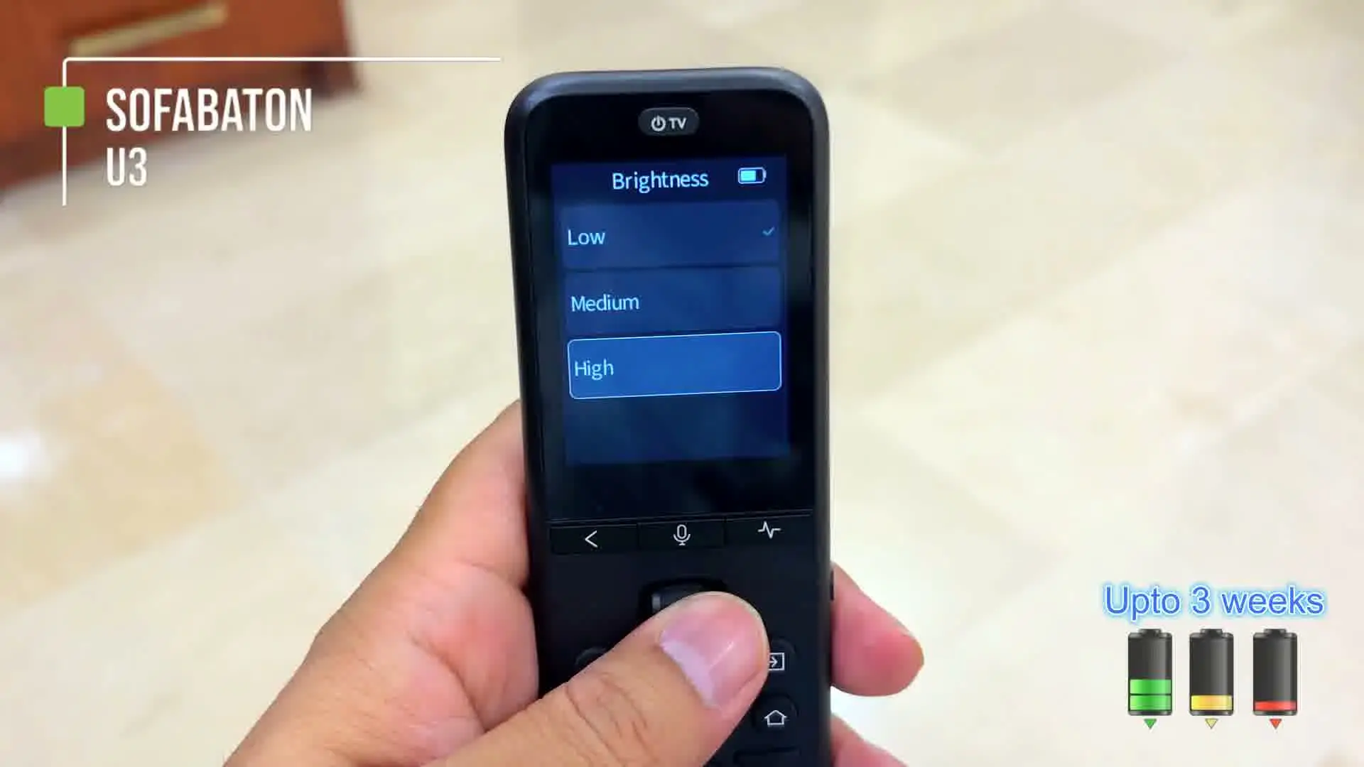 A hand holding the SofaBaton U3 remote showing its Brightness settings screen with a battery icon, next to on-screen graphics reading Upto 3 weeks with three battery level icons