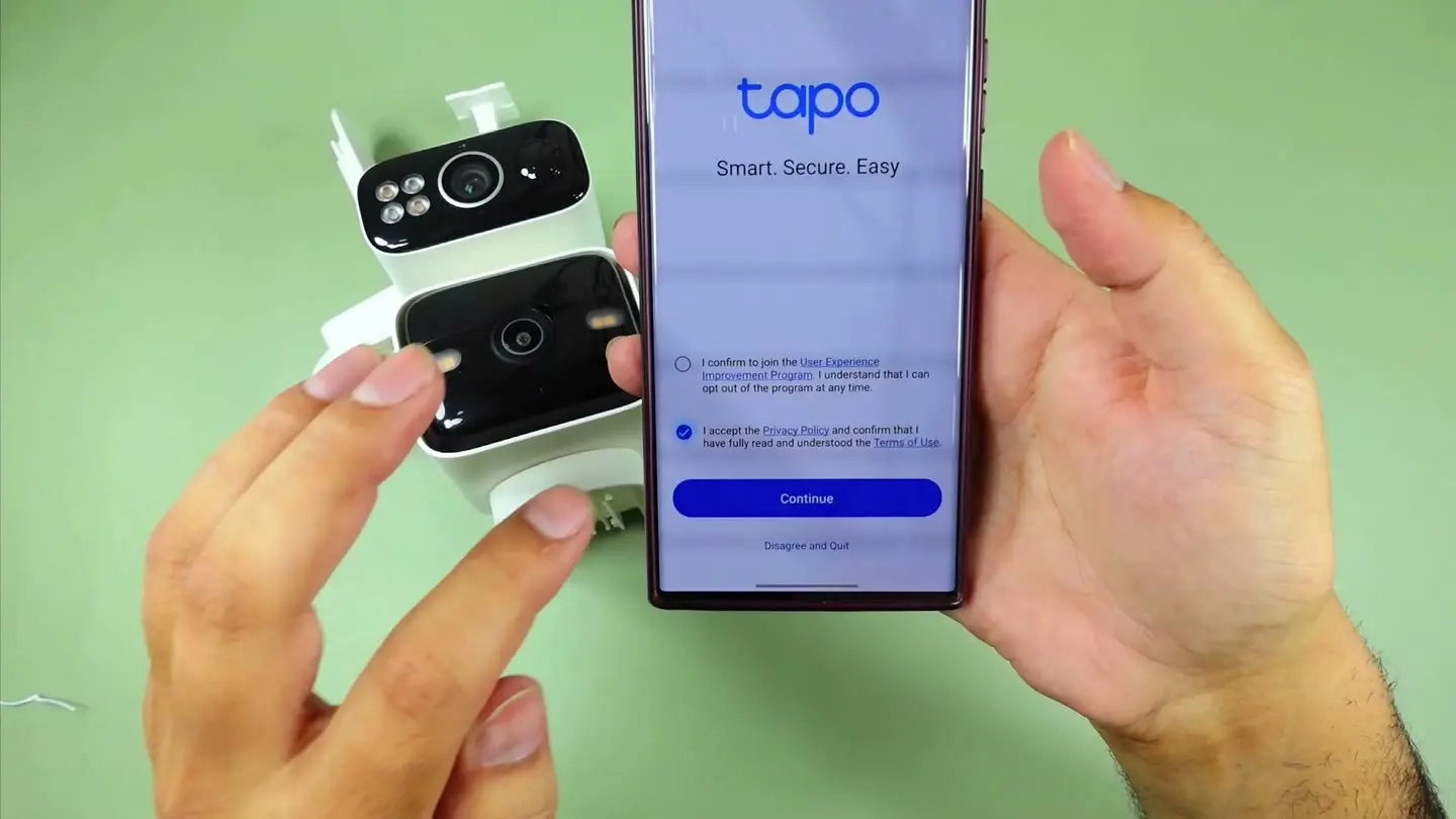 The Tapo app onboarding screen held next to the C645D camera during setup