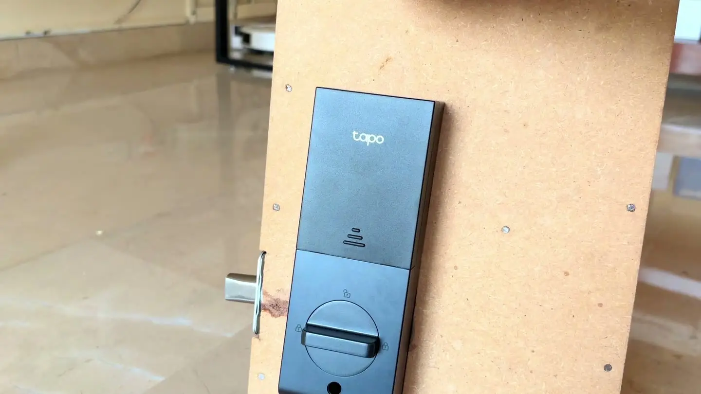 Tapo DL130 smart lock mounted on Tech With RR's lock test board, showing the Tapo branding on the front panel