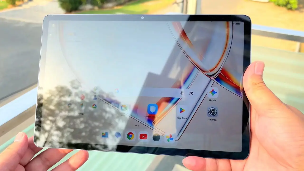 The TCL Tab A1 held outdoors with strong reflections across the screen partly hiding the home screen