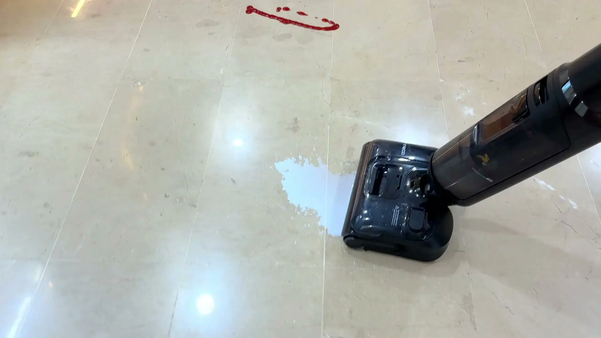 The Tineco FLOOR ONE S7 Stretch Ultra floor washer cleaning a marble floor, its black head passing over a wet patch with a red ketchup mark still ahead of it