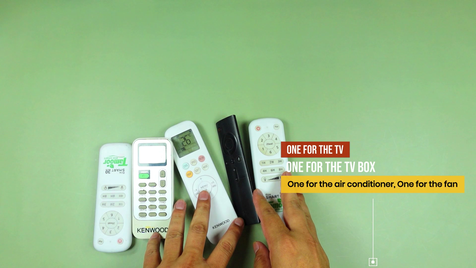 A pile of remotes on a table — a black TV box remote and white remotes for a TV, air conditioner and fan — with on-screen text reading ONE FOR THE TV, ONE FOR THE TV BOX, one for the air conditioner, one for the fan