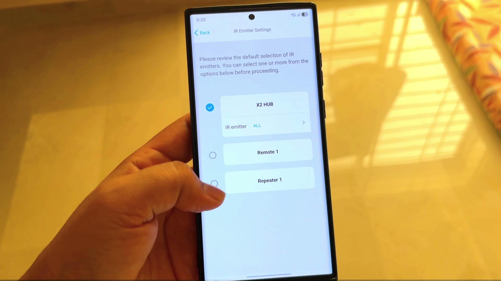 The Sofabaton app's IR Emitter Settings screen on a phone, listing X2 HUB, Remote 1 and Repeater 1 as selectable IR emitters